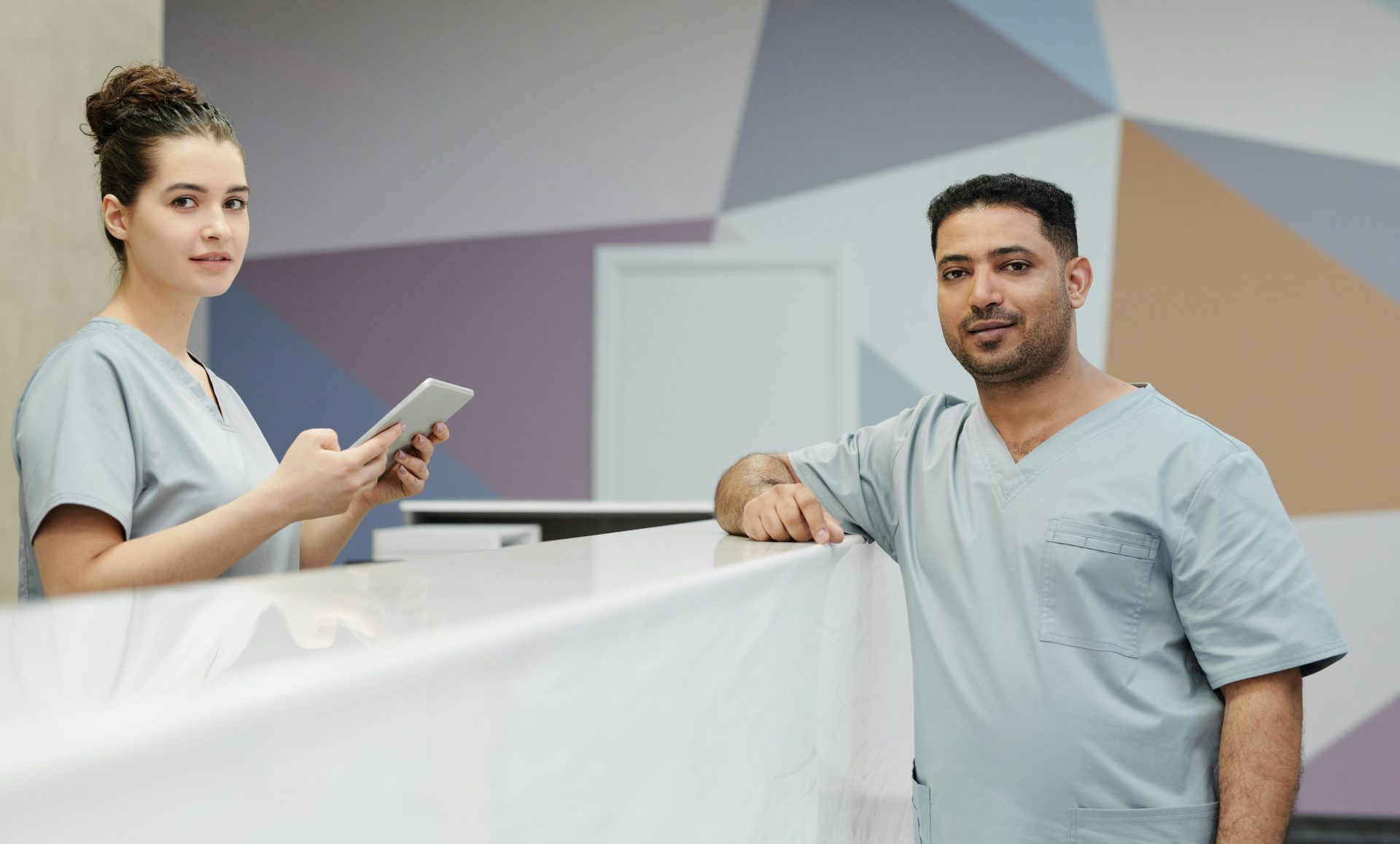 Medizinisches Personal in OP-Kleidung im Empfangsbereich einer modernen Klinik.
